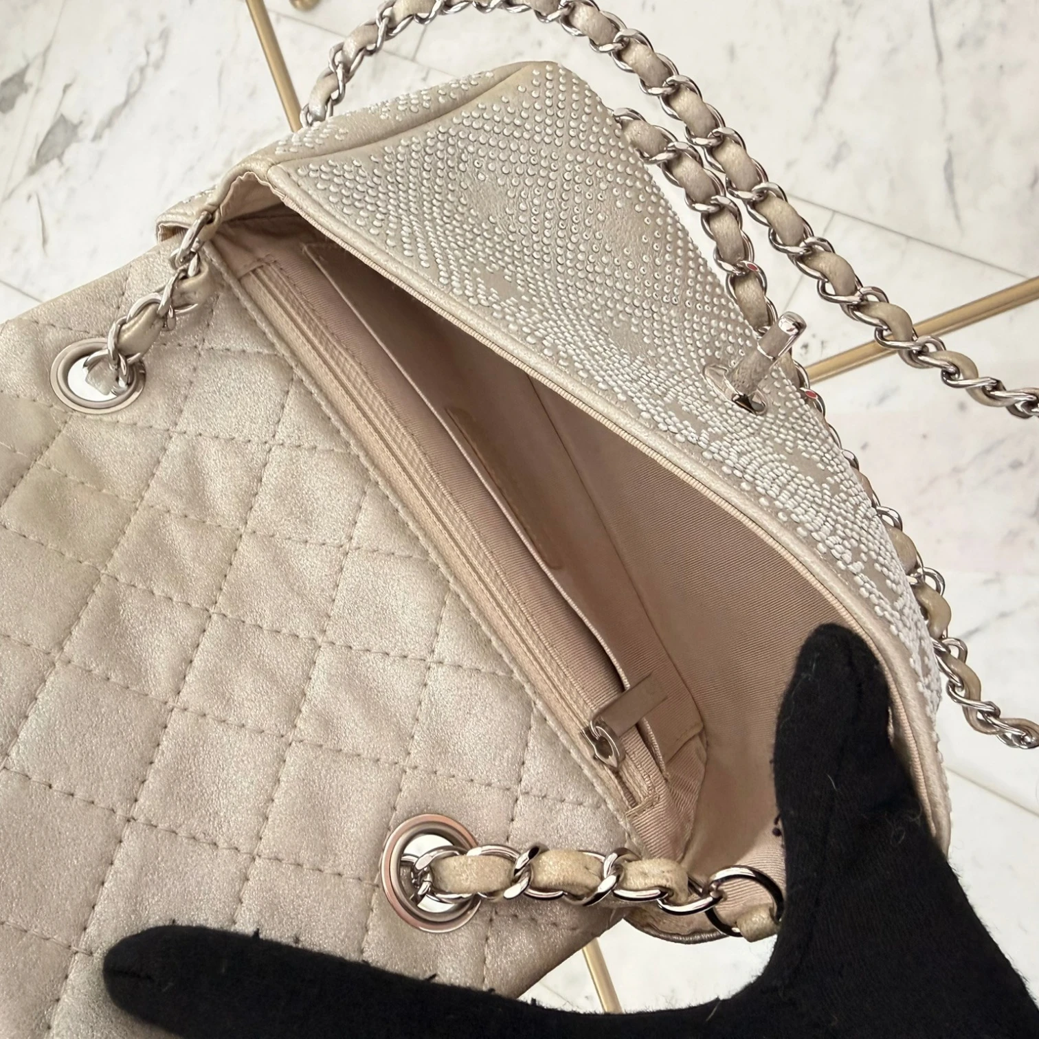 Interior zip and slip pockets of a Chanel iridescent studded calfskin Mini Flap crossbody bag, with a chain strap and silver hardware available in Cyprus at HOUSE of MICY